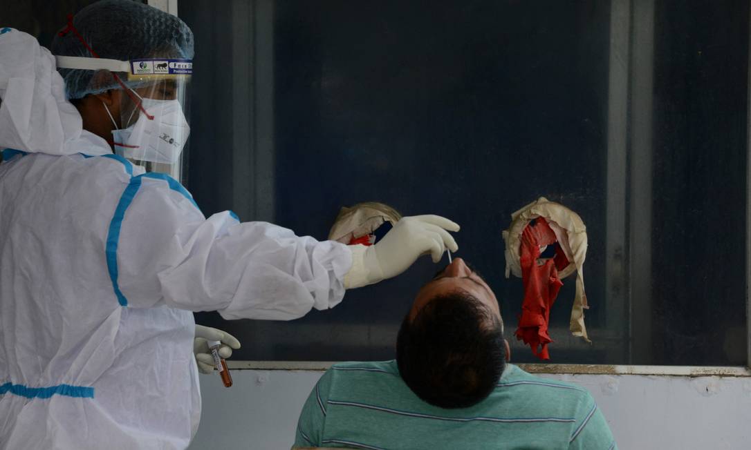 Profissional de saúde coleta esfregaço nasal para teste PCR de Covid-19 para em hospital nos arredores de Siliguri, em maio de 2021 Foto: DIPTENDU DUTTA / AFP