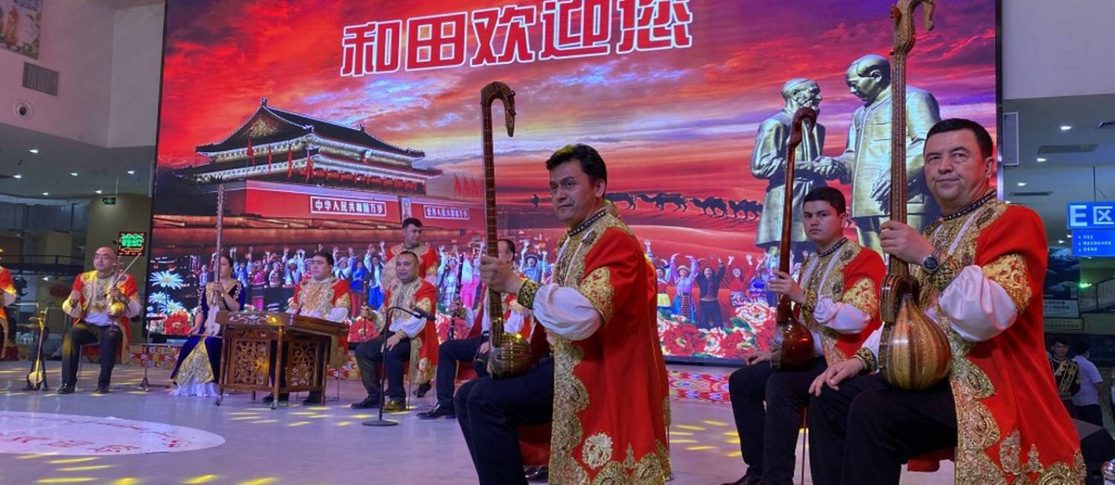 Show de música uigur em Hotan; ao fundo, imagens da Cidade Proibida e de Mao Tsé-tung (à direita) Foto: Marcelo Ninio / Agência O Globo