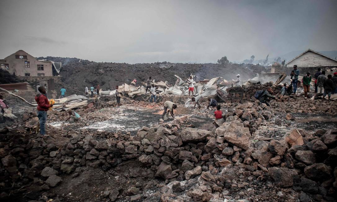 Moradores no leste da República Democrática do Congo, próximos à cidade de Goma, vasculham a área após lava do vulcão Nyiragongo passar pelo local Foto: Guerchom Ndebo / AFP