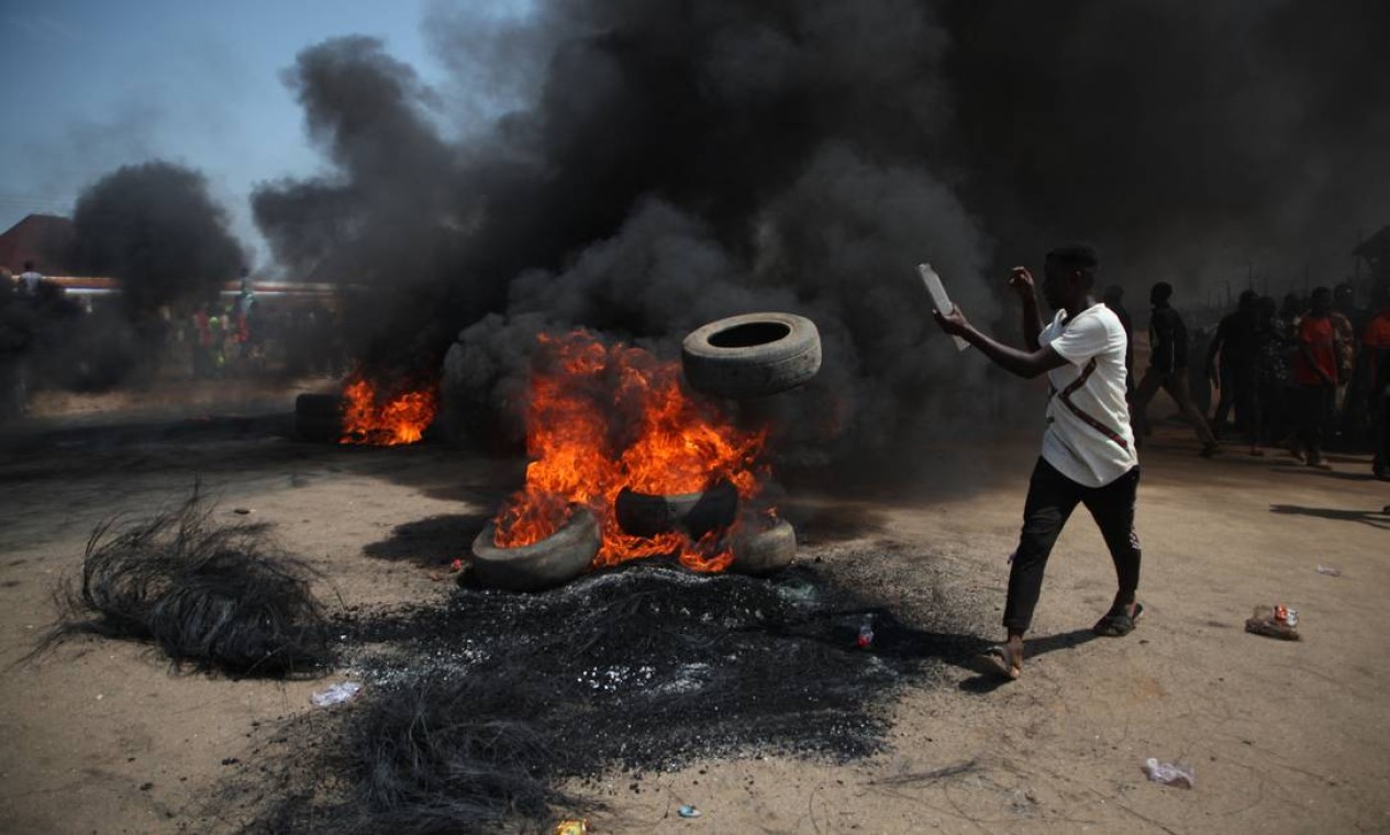 Homem atira um pneu para uma barricada em chamas na rodovia Kaduna-Abuja, em Gauruka, Nigéria, durante protesto motivados pelo sequestro em que 16 pessoas e foram capturadas e três, mortas, no estado de Níger Foto: KOLA SULAIMON / AFP