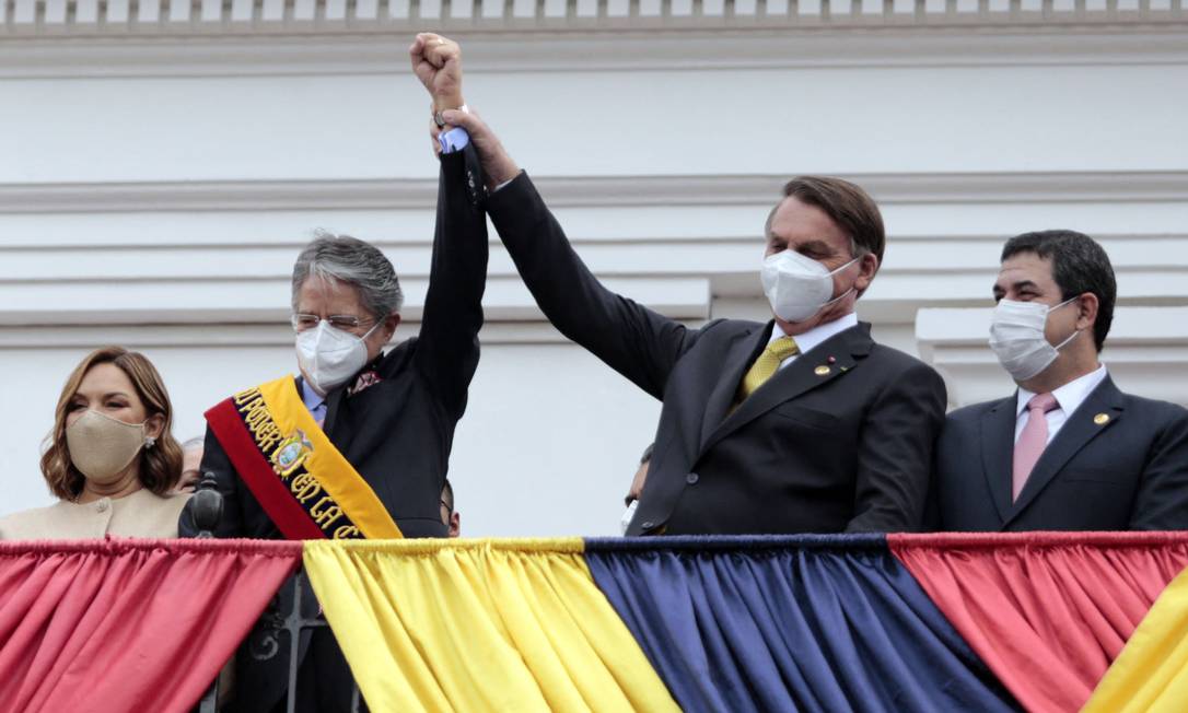 Jair Bolsonaro levanta o braço do novo presidente do Equador, Guillermo Lasso, durante sua posse em Quito Foto: STR / AFP