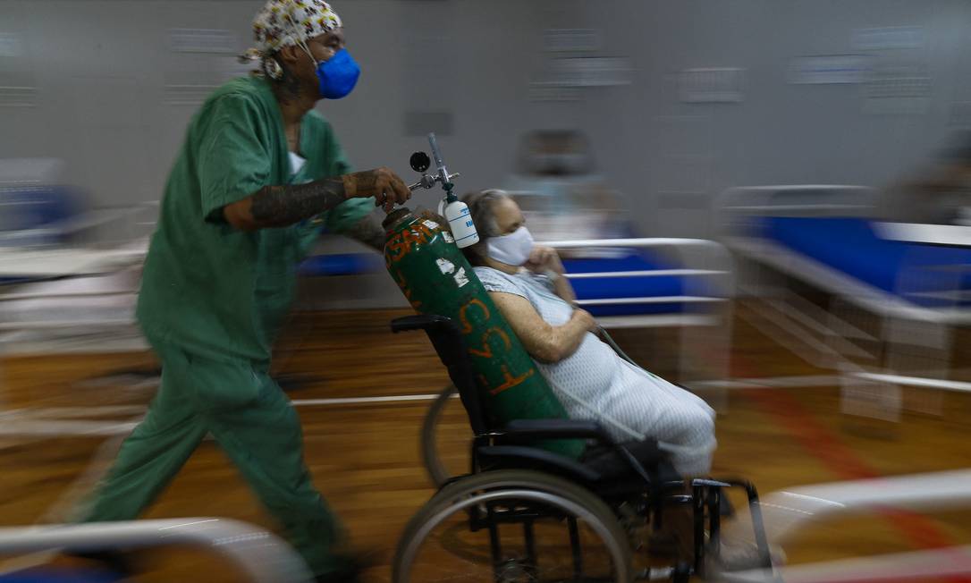 Profissional de saúde leva paciente de Covid-19 a um hospital de campanha montado em uma quadra esportiva em Santo André (SP) Foto: Miguel SCHINCARIOL/AFP/26-3-2021