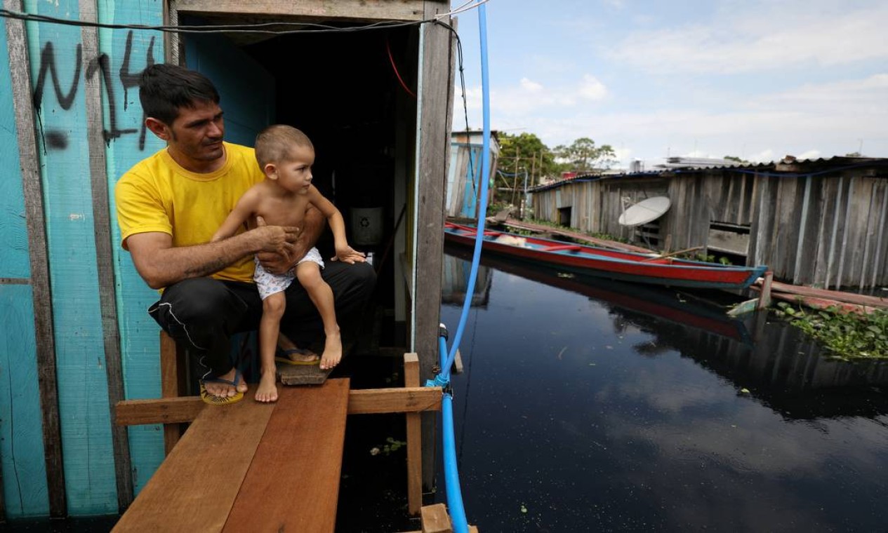 Valdemir Messias e seu filho Emanuel Barros Messias, em frente a sua casa em meio à cheia do Rio Negro, na capital do Amazonas Foto: BRUNO KELLY / REUTERS