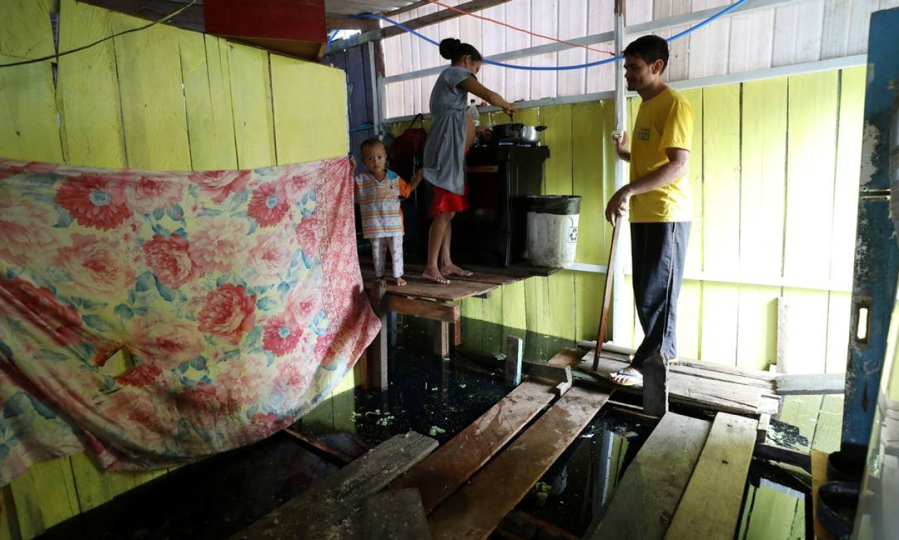 Valdemir Messias ajuda sua esposa, grávida de nove meses, Andrea Rodrigues, ao lado de seu filho Natanael Barros Messias, dentro de sua casa inundada, em Manaus Foto: BRUNO KELLY / REUTERS