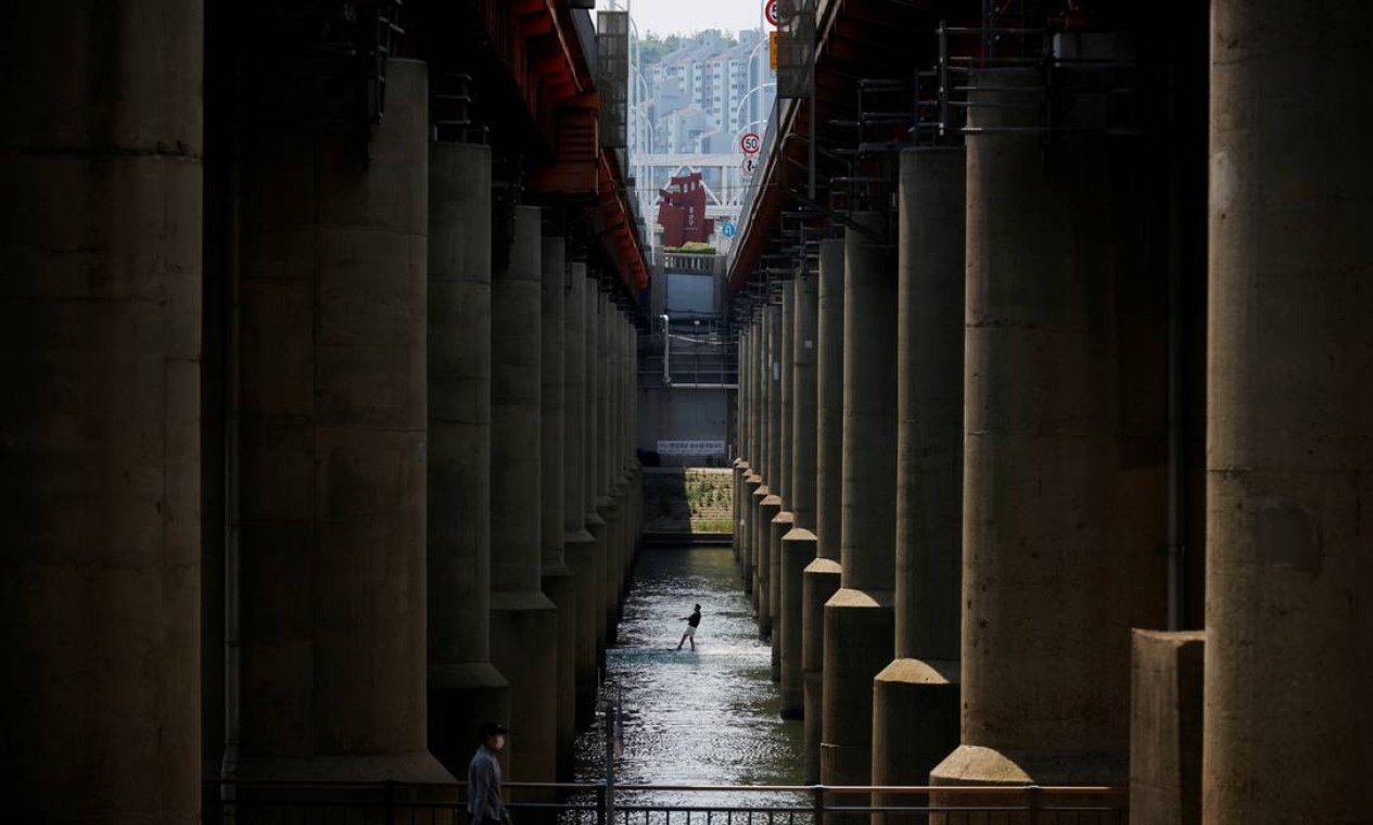 Um homem pratica wakeboard debaixo de uma ponte, no rio Han em Seul, Coreia do Sul Foto: KIM HONG-JI / REUTERS