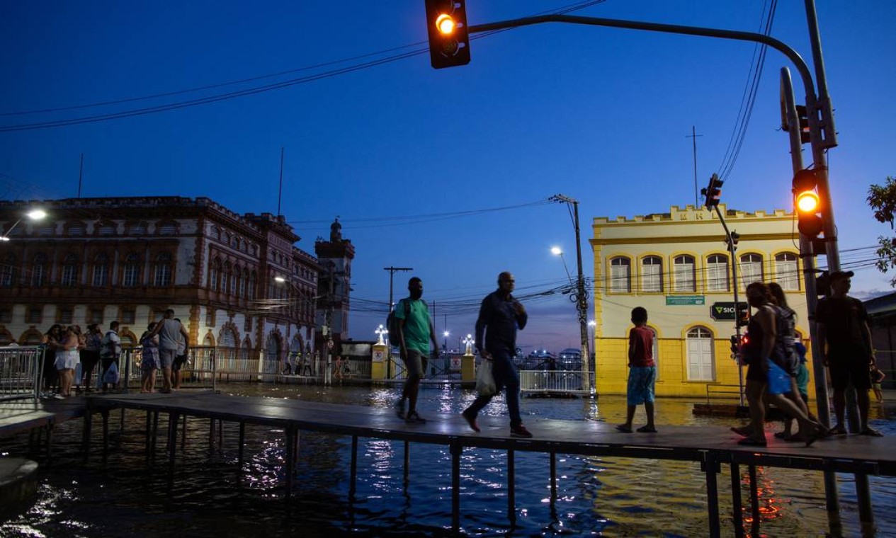 Pessoas caminham sobre pontes improvisadas para atravessar ruas inundadas no centro de Manaus, no Amazonas, durante cheia recorde do Rio Negro, que atingiu 29,97 metros Foto: MICHAEL DANTAS / AFP
