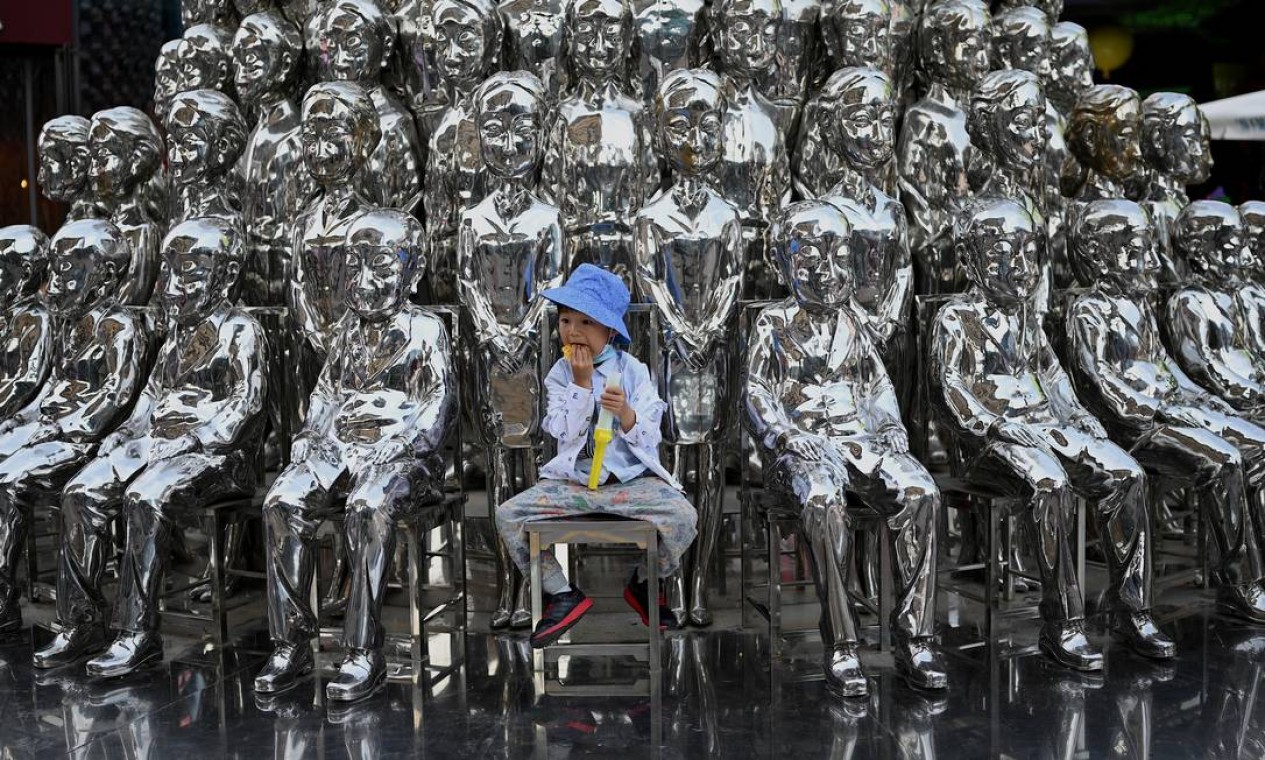 Menino posa ao centro de esculturas em exibição em um shopping no Dia Internacional da Criança, em Pequim, um dia depois que a China anunciou que permitiria aos casais terem até três filhos Foto: NOEL CELIS / AFP