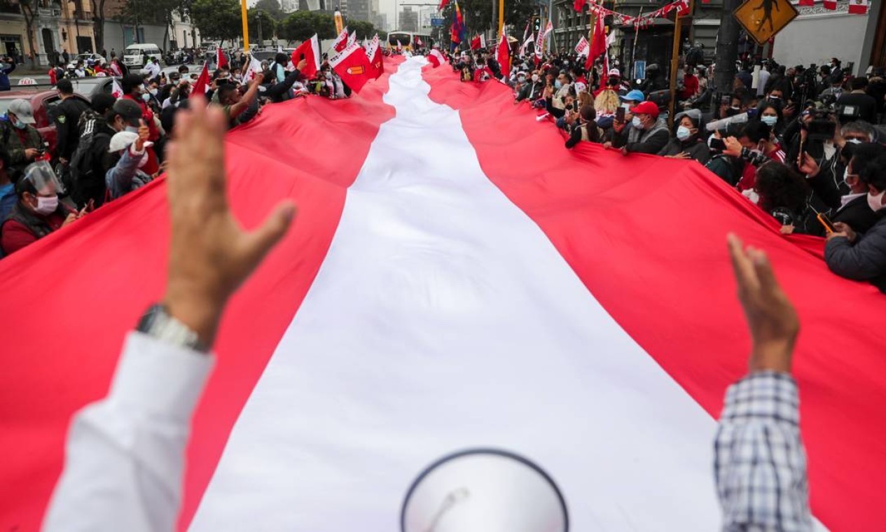 Apoiadores do candidato à presidência do Peru, Pedro Castillo, carregam uma bandeira peruana enorme na rua no dia seguinte ao segundo turno, em Lima, Peru Foto: SEBASTIAN CASTANEDA / REUTERS