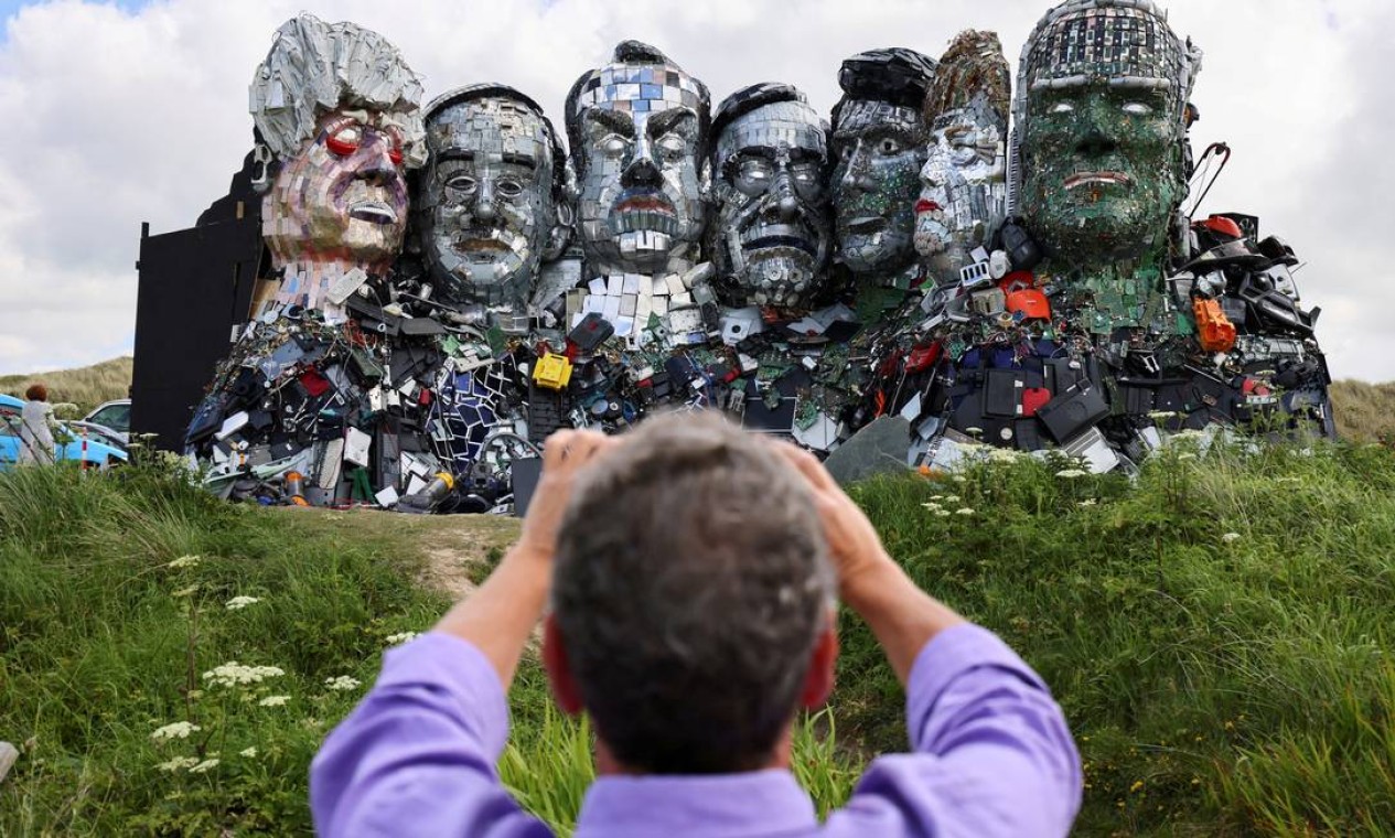 Um homem fotografa "Mount Recyclemore", uma obra de arte que mostra os líderes do G7 feito de lixo eletrônico por Joe Rush e Alex Wreckage, antes da cúpula do G7, em Hayle Towans em Cornwall, Grã-Bretanha Foto: TOM NICHOLSON / REUTERS