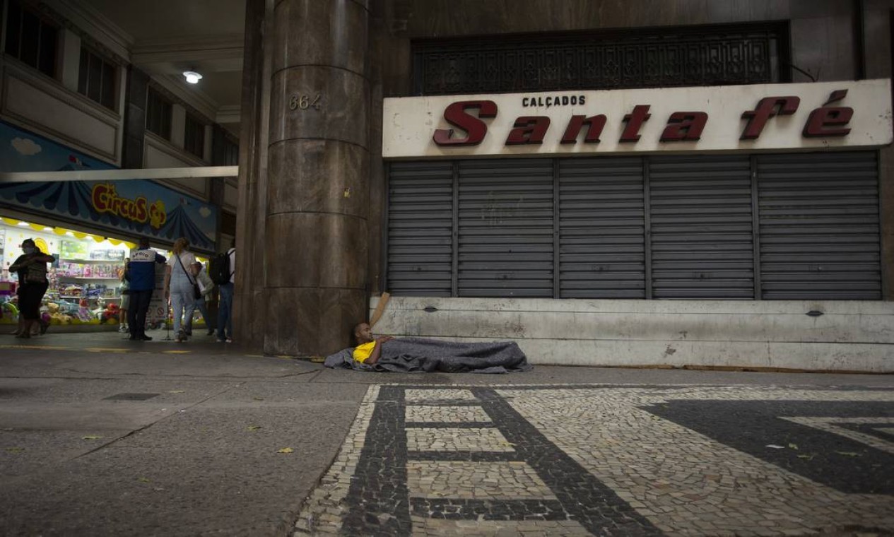 Pessoa em situação de rua dorme diante da fachada da loja de calçados Santa Fé, na Galeria Menescal, fechada há cerca de 4 anos Foto: Márcia Foletto / Agência O Globo