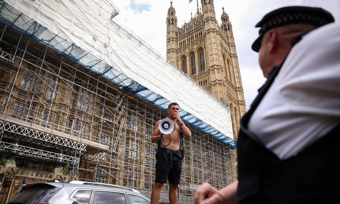 Um manifestante usa um megafone durante um protesto perto do Parlamento. Diante do aumento de casos de Covid-19 no Reino Unido, o primeiro-ministro, Boris Johnson, anunciou, nesta segunda-feira, o adiamento do fim das restrições anticovid Foto: HENRY NICHOLLS / REUTERS