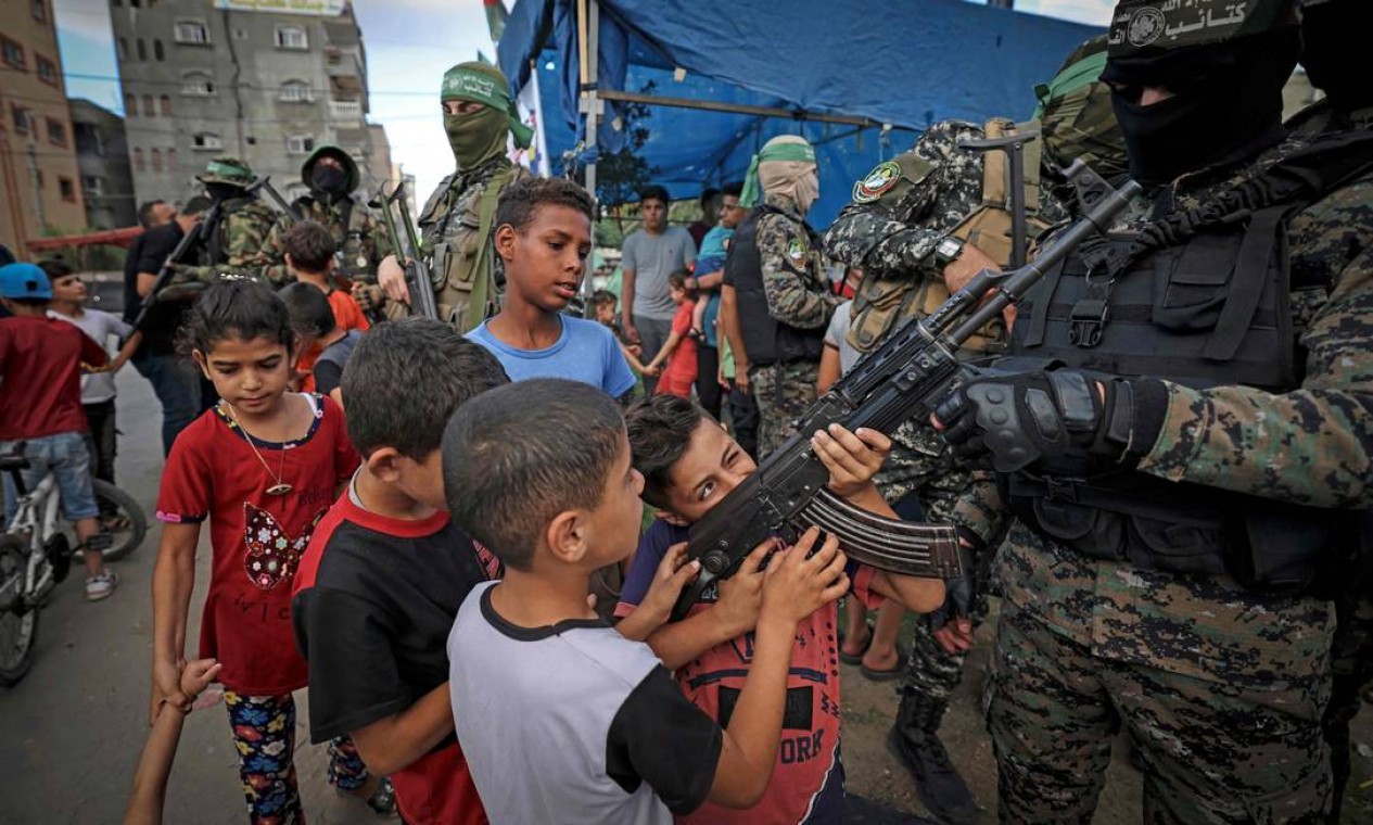 Meninos palestinos seguram uma arma pertencente a um membro das Brigadas Ezz-Al Din Al-Qassam na Cidade de Gaza Foto: MAHMUD HAMS / AFP