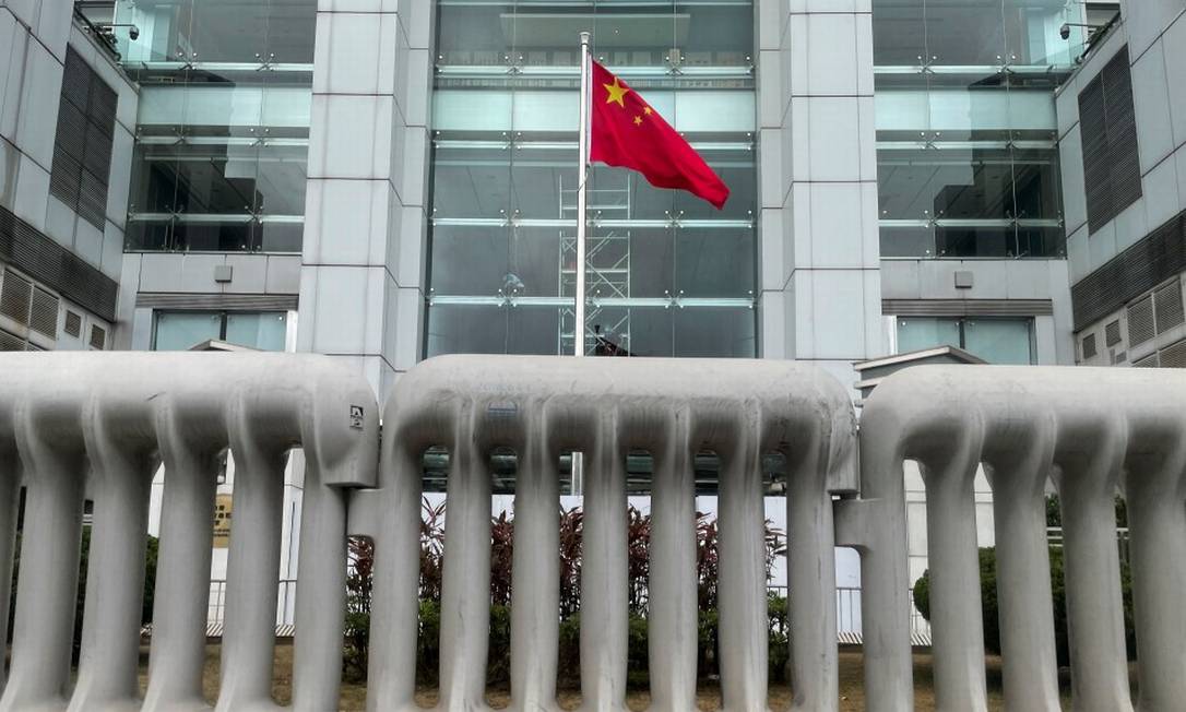 Bandeira da China hasteada atrás de barreiras que protegem o Escritório do governo chinês no território semiautônomo de Hong Kong Foto: TYRONE SIU / REUTERS/12-6-2021