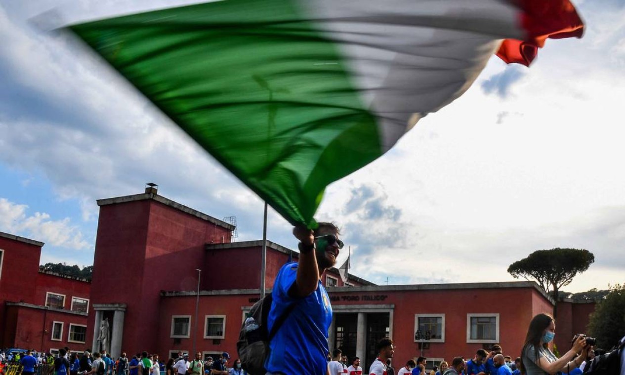 Torcedor da Itália agita a bandeira nacional ao chegar ao estádio olímpico, em Roma, antes do início do jogo contra Turquia, na abertura da Eurocopa Foto: TIZIANA FABI / AFP