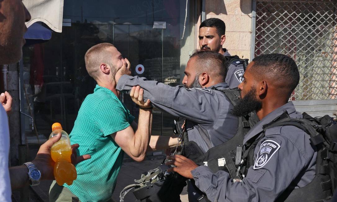 Integrante das forças de segurança isralenses empurra homem palestino em Jerusalém Oriental durante protesto contra marcha nacionalista Foto: MENAHEM KAHANA / AFP