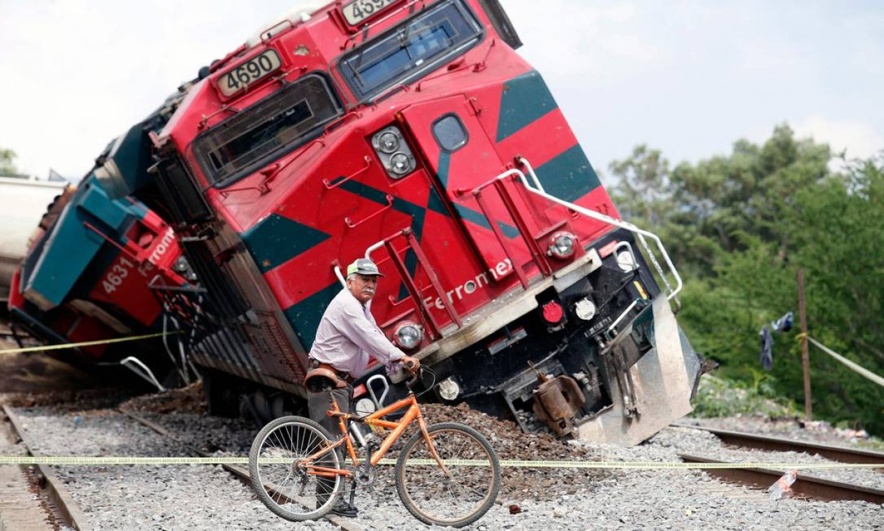 Homem com uma bicicleta passa por um trem que descarrilou na comunidade de San Isidro Mazatepec em Tala, Estado de Jalisco, México, onde um trem de carga descarrilou e tombou sobre casas, matando um residente e ferindo três outros Foto: ULISES RUIZ / AFP