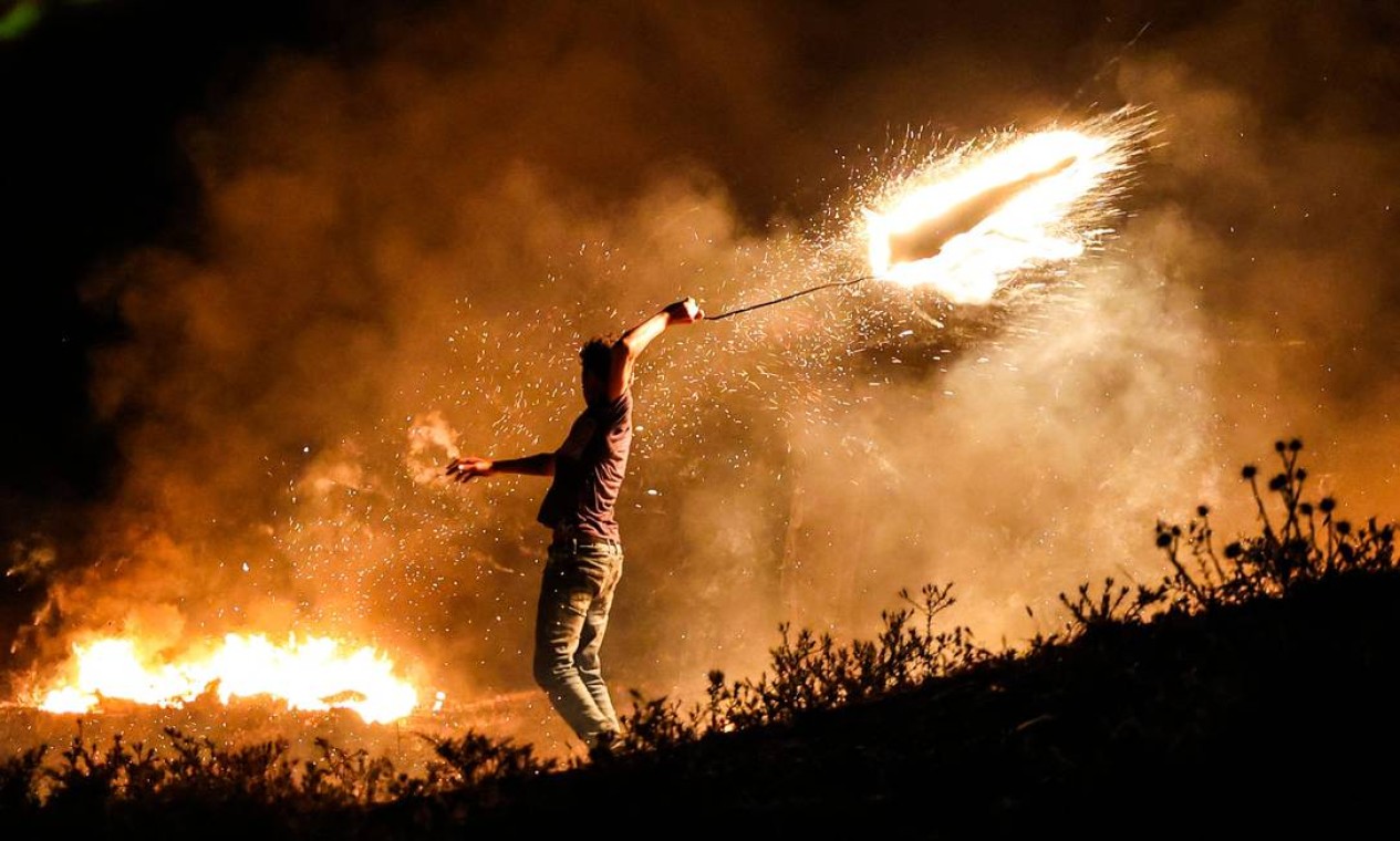 Manifestante palestino lança um projétil em chamas contra as forças israelenses durante uma manifestação a leste da Cidade de Gaza Foto: MAHMUD HAMS / AFP
