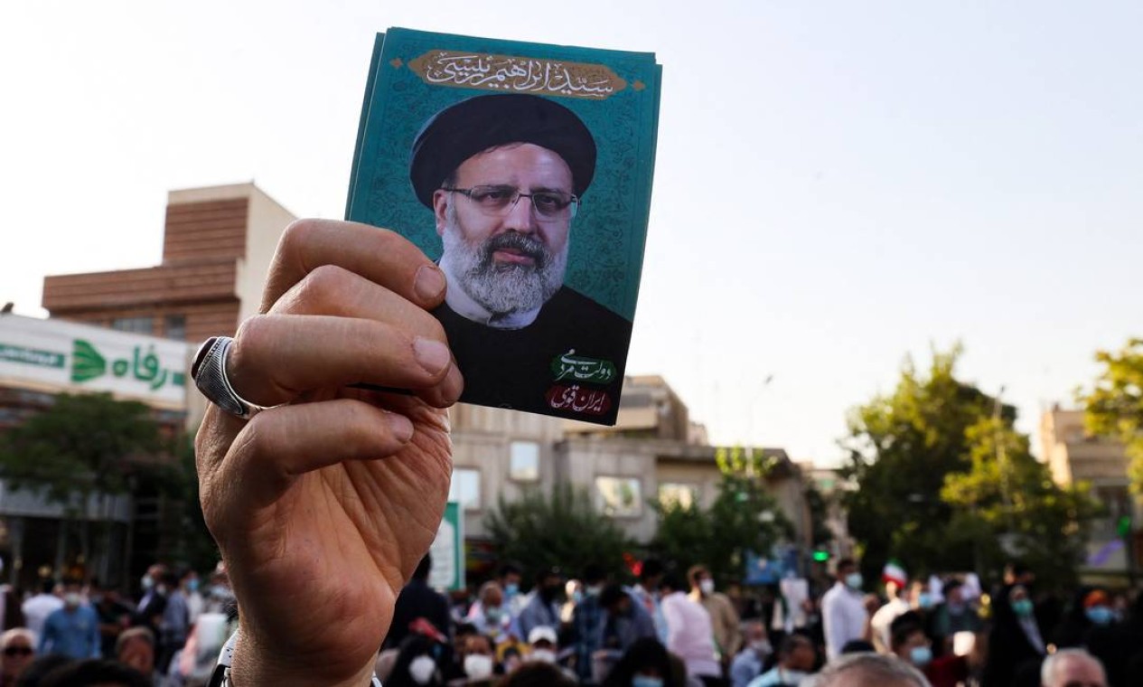 Apoiador do ultraconservador candidato presidencial iraniano Ebrahim Raisi levanta seu retrato durante um comício na capital Teerã, antes da eleição presidencial na república islâmica Foto: ATTA KENARE / AFP