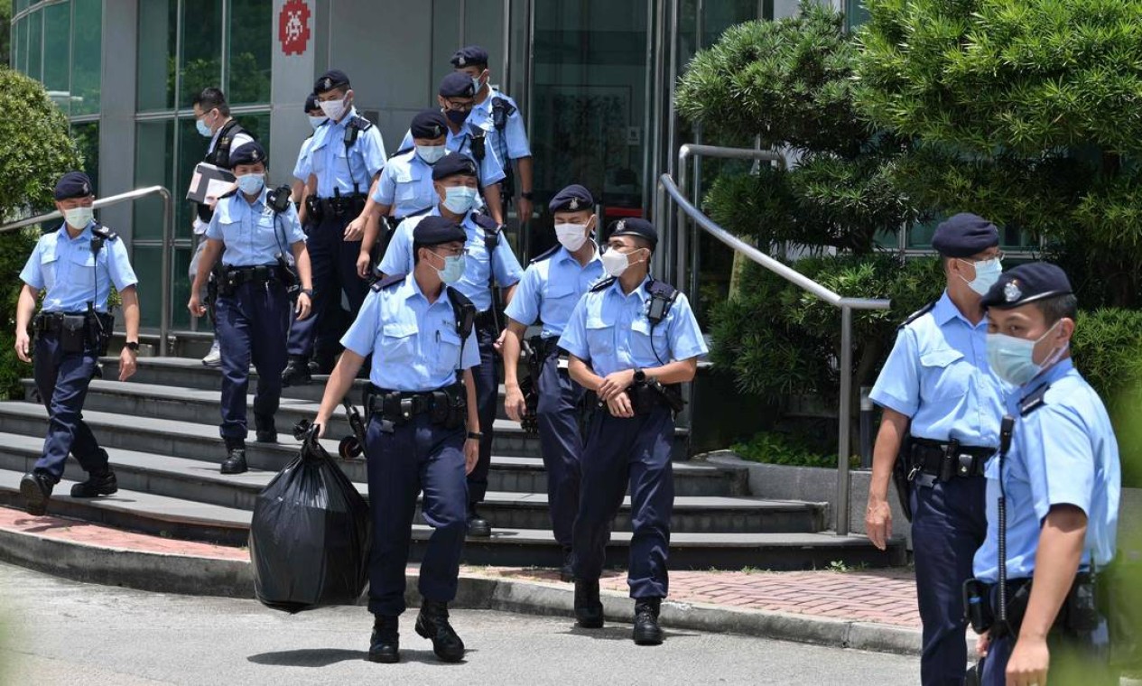 Policiais deixam os escritórios do jornal Apple Daily em Hong Kong com apreensões, depois de dois executivos e três editores serem presos Foto: ANTHONY WALLACE / AFP