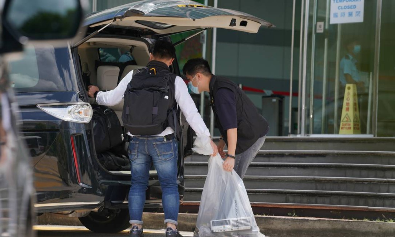 Policiais do departamento de segurança nacional colocam itens apreendidos em uma van da polícia em frente aos escritórios do Apple Daily e Next Media em Hong Kong Foto: LAM YIK / REUTERS