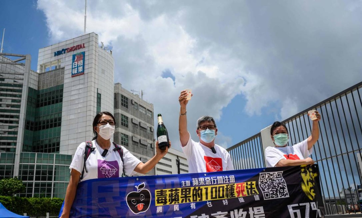 Ativistas pró-governo comemoram com champanhe fora dos escritórios do jornal local Apple Daily Foto: ANTHONY WALLACE / AFP