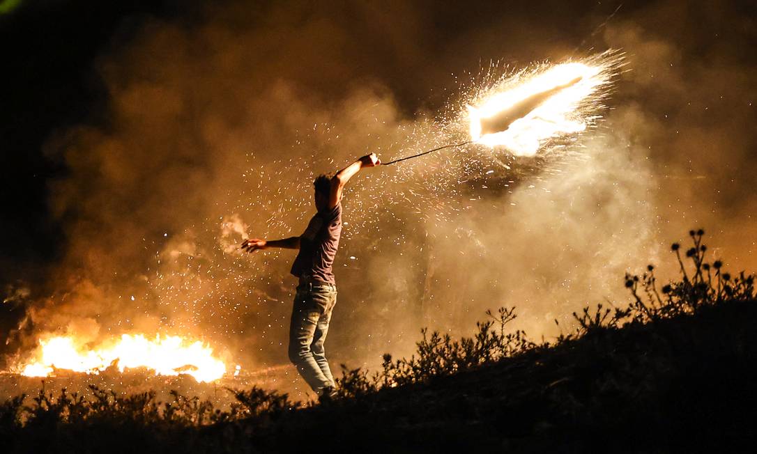 Un manifestante palestinese spara una granata fiammeggiante contro le forze israeliane durante una manifestazione a est di Gaza City, al confine israeliano, per protestare contro la marcia della bandiera israeliana nella Città Vecchia di Gerusalemme Foto: MAHMUD HAMS / AFP