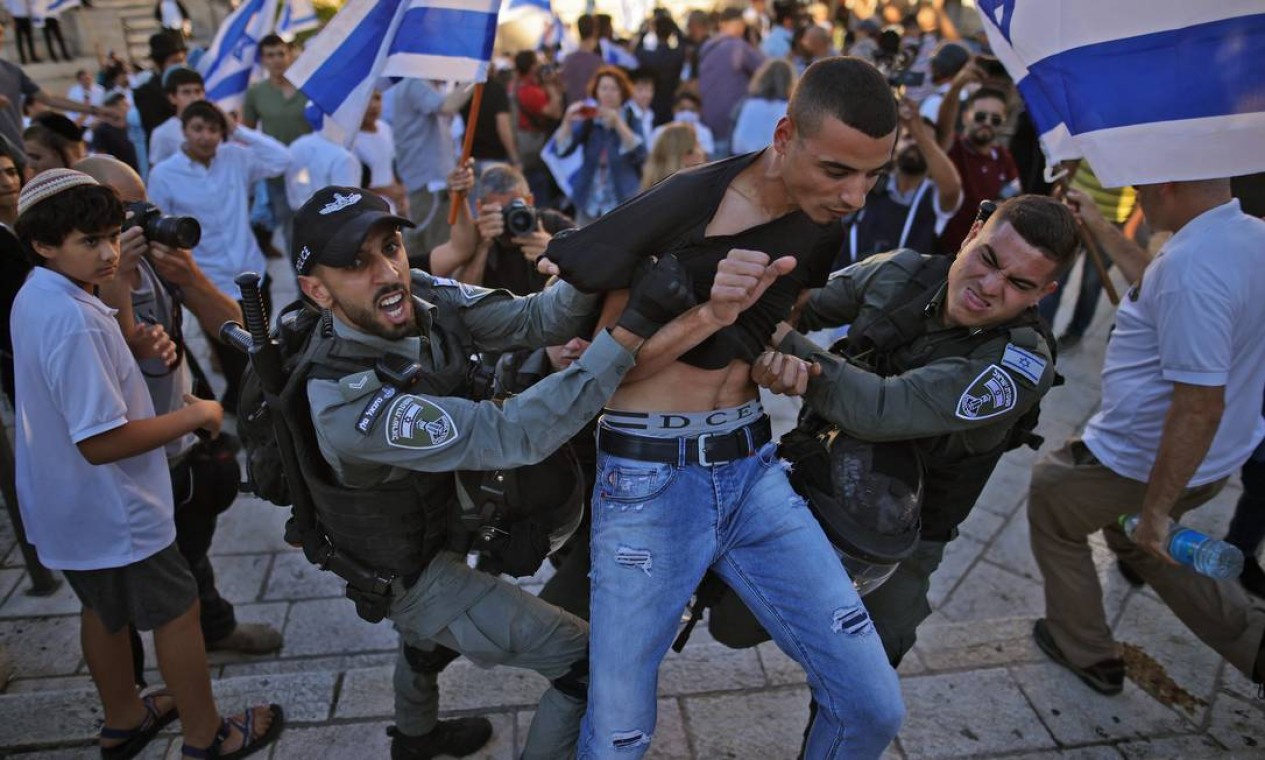 Oficiais de segurança israelenses brigam com um palestino enquanto ultranacionalistas participam da Marcha das Bandeiras perto da Cidade Velha de Jerusalém Foto: AHMAD GHARABLI / AFP