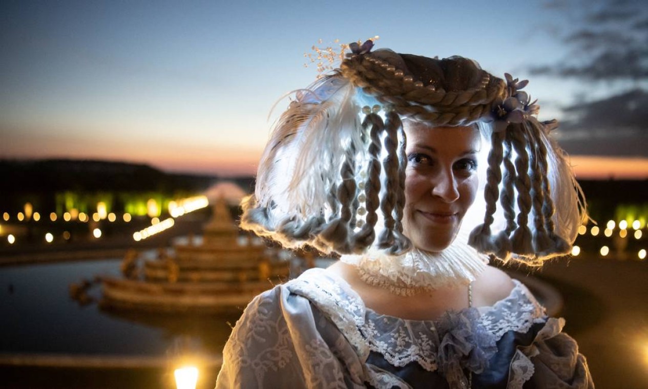 Mulher vestida com traje do período barroco posa para uma fotografia no parque do Palácio Real de Versalhes, a sudoeste de Paris, durante a reabertura do "Night Fountains Show" Foto: ALAIN JOCARD / AFP