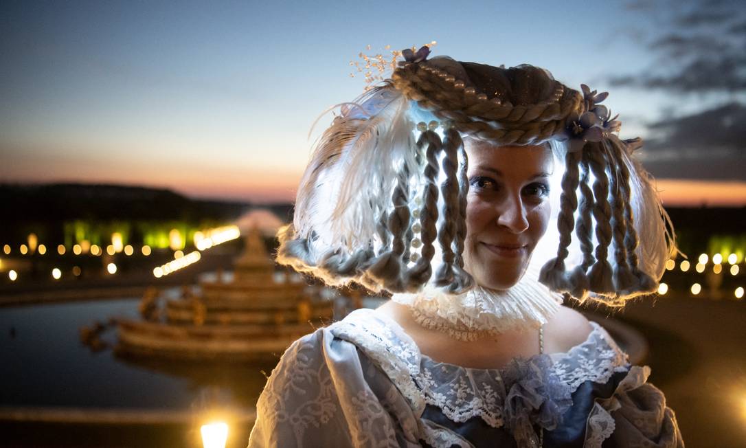 Una donna in costume barocco posa per una fotografia nel giardino del Palais Royal a Versailles, a sud-ovest di Parigi, durante la riapertura & # 034;  Spettacolo notturno delle fontane & # 034;  Foto: ALAIN JOCARD / AFP