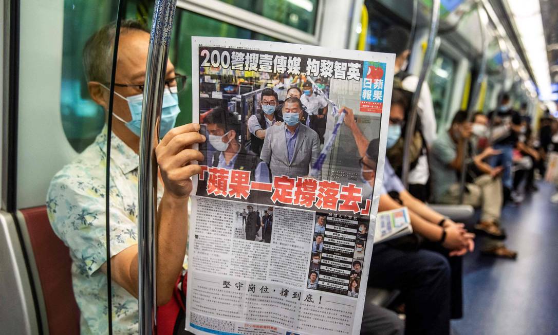 Homem lê edição impressa do Apple Daily durante viagem de trem em Hong Kong Foto: ISAAC LAWRENCE / AFP/11-08-2020