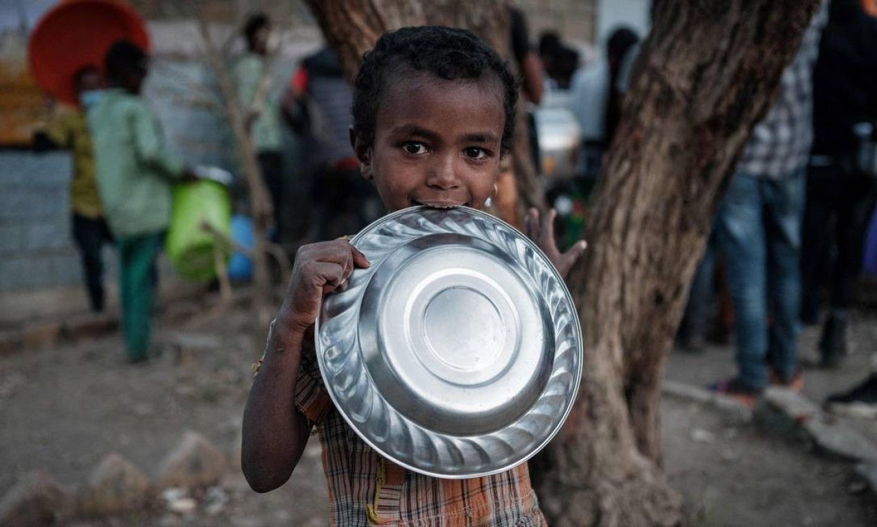Criança que fugiu da violência na região de Tigray, na Etiópia, espera por um jantar como a única refeição do dia na escola primária de May Weyni. A instituição está hospedando mais de 7,3 mil pessoas deslocadas, em Mekele, capital de Região de Tigray, Etiópia Foto: YASUYOSHI CHIBA / AFP
