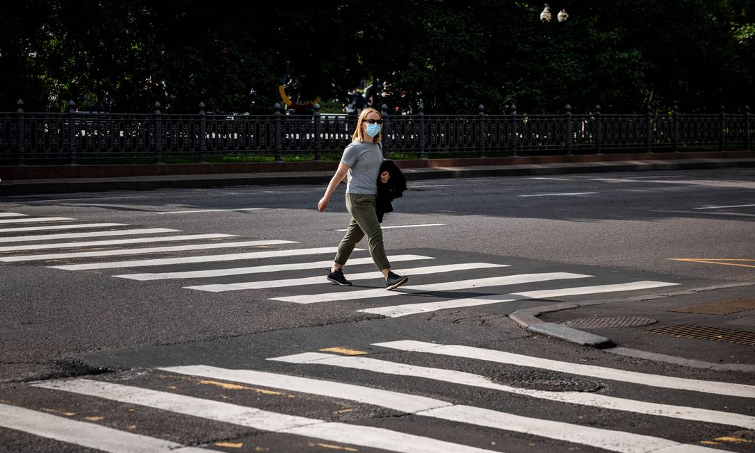 Mulher usando máscara facial caminha em uma faixa de pedestres em Moscou, quando o prefeito da capital russa, Sergei Sobyanin, anunciou uma semana 