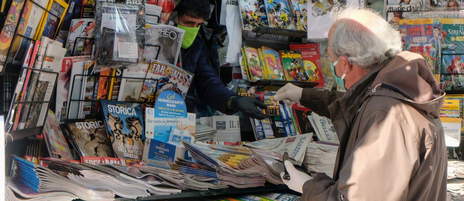 Homem de máscara faz compras em uma banca de jornal em Veneza, na Itália, durante pandemia da Covid-19 Foto: MANUEL SILVESTRI / REUTERS