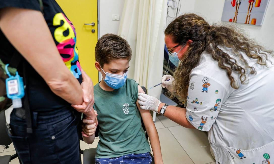 Adolescente recebe dose da vacina da Pfizer em Tel Aviv. Israel defende expansão da vacinação entre mais jovens para conter novos surtos da Covid-19 Foto: JACK GUEZ / AFP
