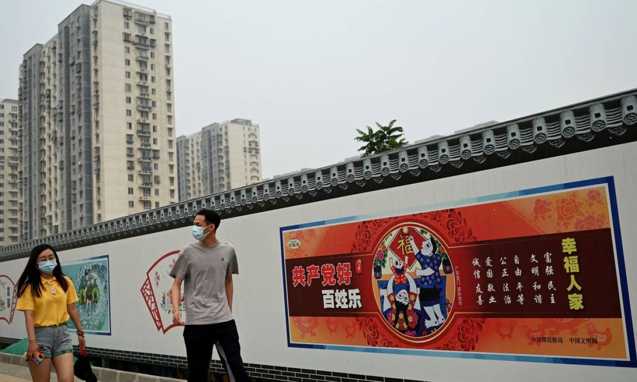 Em Pequim, pessoas passam por uma propaganda que diz que "o comunismo é bom. Pessoas felizes: prosperidade, democracia, civilidade, harmonia, liberdade, igualdade, justiça, Estado de direito, patriotismo, dedicação, integridade e simpatia" Foto: NOEL CELIS / AFP