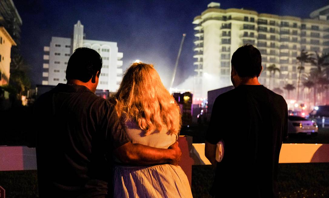 Pessoas assistem ao trabalho das equipes de emergência que continuam as operações de busca e resgate para sobreviventes em Surfside, perto de Miami Beach, Flórida Foto: MARIA ALEJANDRA CARDONA / REUTERS