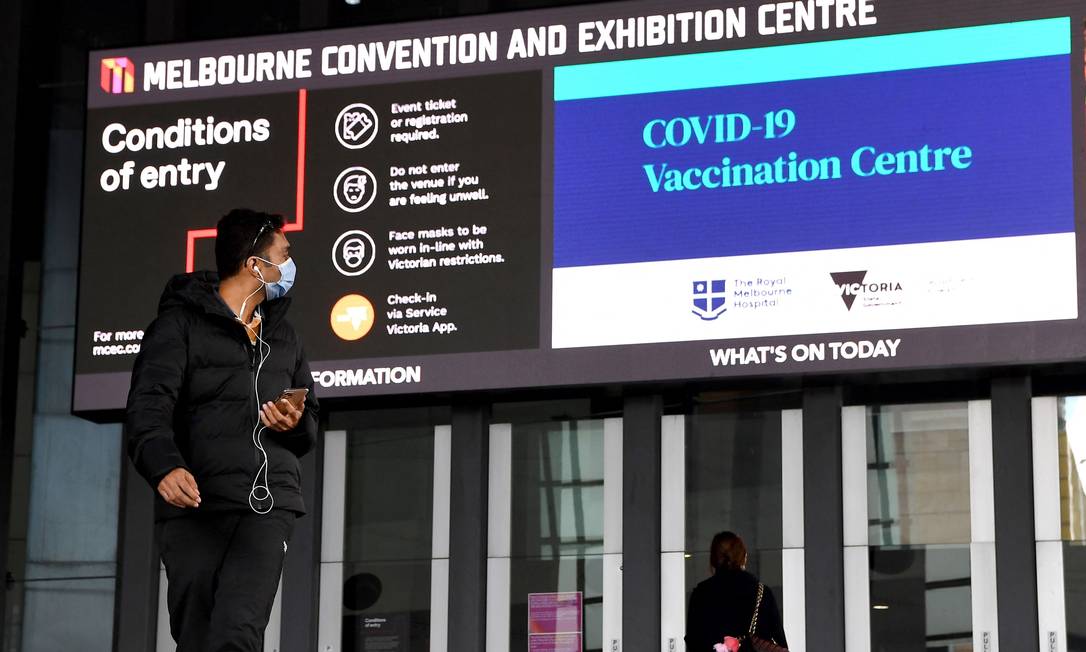 Homem passa por um centro de vacinação Covid-19 em Melbourne Foto: WILLIAM WEST / AFP