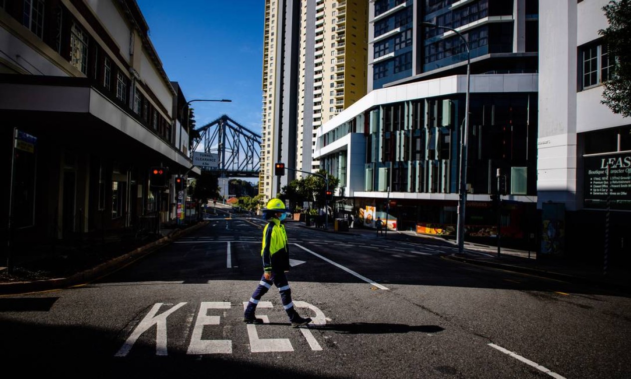 Leonela Gonzalez, trabalhadora de controle de tráfego, atravessa uma rua deserta em Brisbane Foto: PATRICK HAMILTON / AFP
