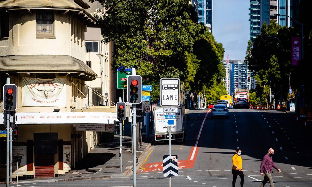 Os pedestres cruzam rua quase deserta em Brisbane Foto: PATRICK HAMILTON / AFP