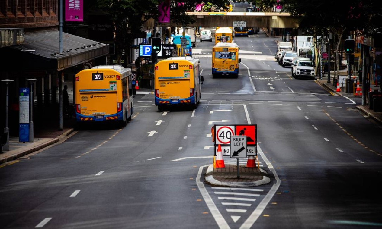 Os ônibus passam ao longo de uma rua em Brisbane, enquanto a cidade fica em recolhida após bloqueio nacional contra surtos da variante Delta da Covid-19, altamente contagiosa Foto: PATRICK HAMILTON / AFP