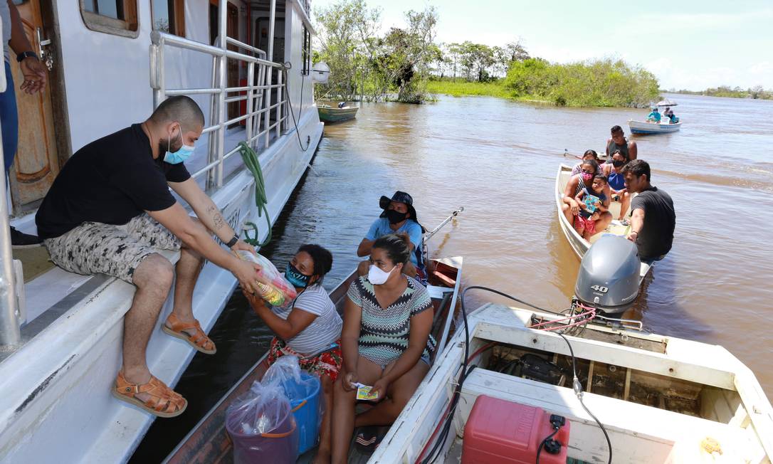 Cestini essenziali vengono distribuiti in barca ai residenti isolati della comunità di Santa Luzia, Erranduba Foto: Euzivaldo Queiroz / Agência O Globo
