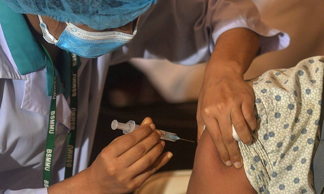 Profissional de saúde aplica vacina contra a Covid-19 Foto: MUNIR UZ ZAMAN / AFP