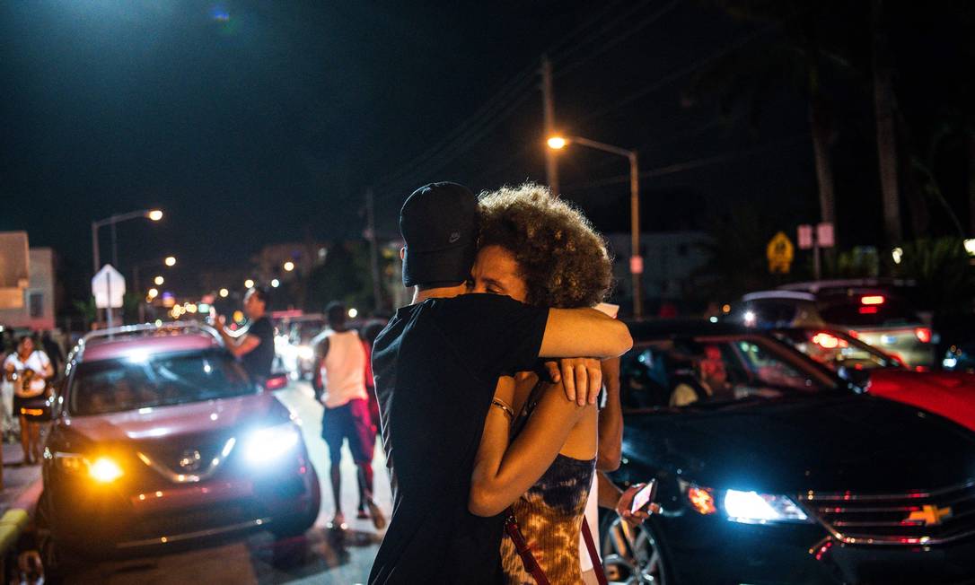 Pessoas se abraçam durante implosão do edifício que desabou parcialmente em Surfside, Flórida, ao norte de Miami Beach, EUA. Ainda há busca por vítimas Foto: CHANDAN KHANNA / AFP