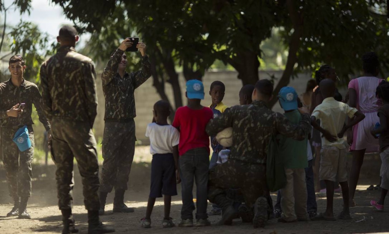 Militares brasileiros tiram fotos com crianças da Escola Sagrado Coração de Jesus, em Porto Principe. Missão de paz da ONU durou 13 anos no país Foto: Daniel Marenco / Agência O Globo - 29/08/2017