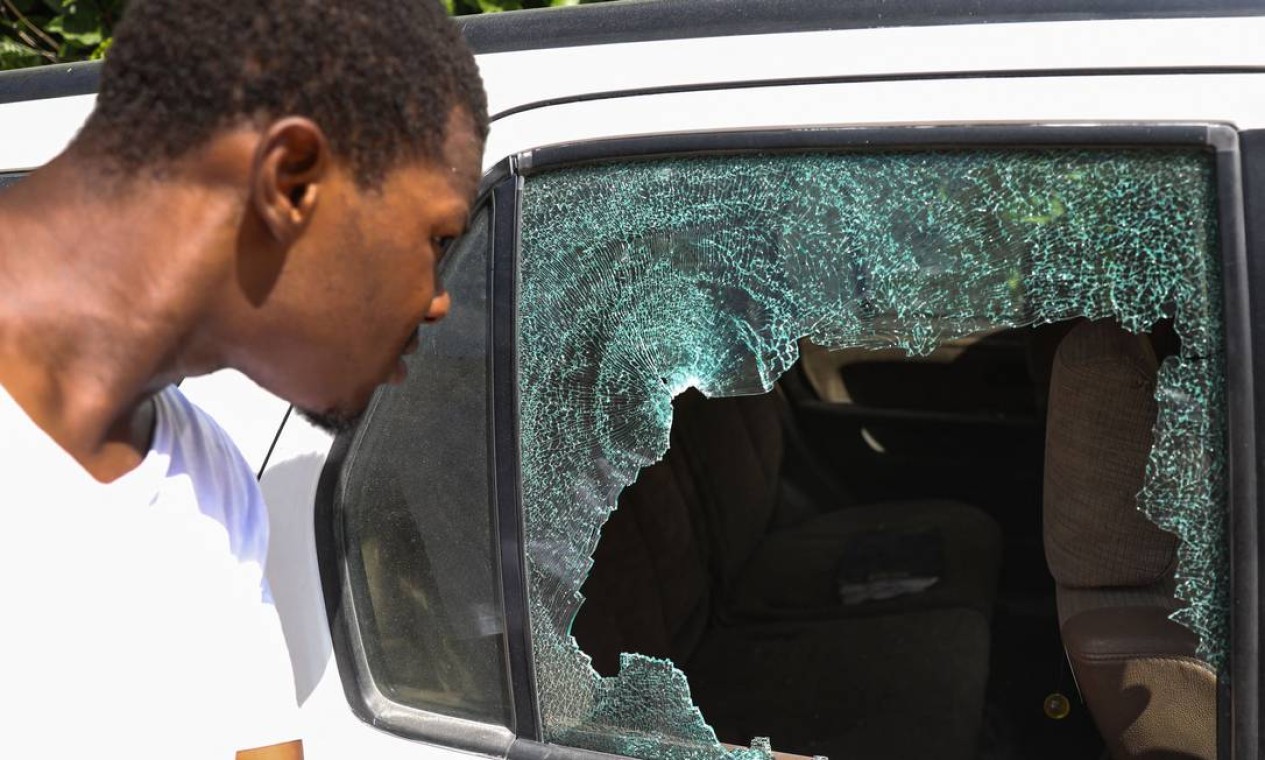 Homem olha para buracos de bala em um carro do lado de fora da residência presidencialem Porto Príncipe, Haiti. O presidente Jovenel Moise foi assassinado e sua esposa ferida Foto: VALERIE BAERISWYL / AFP