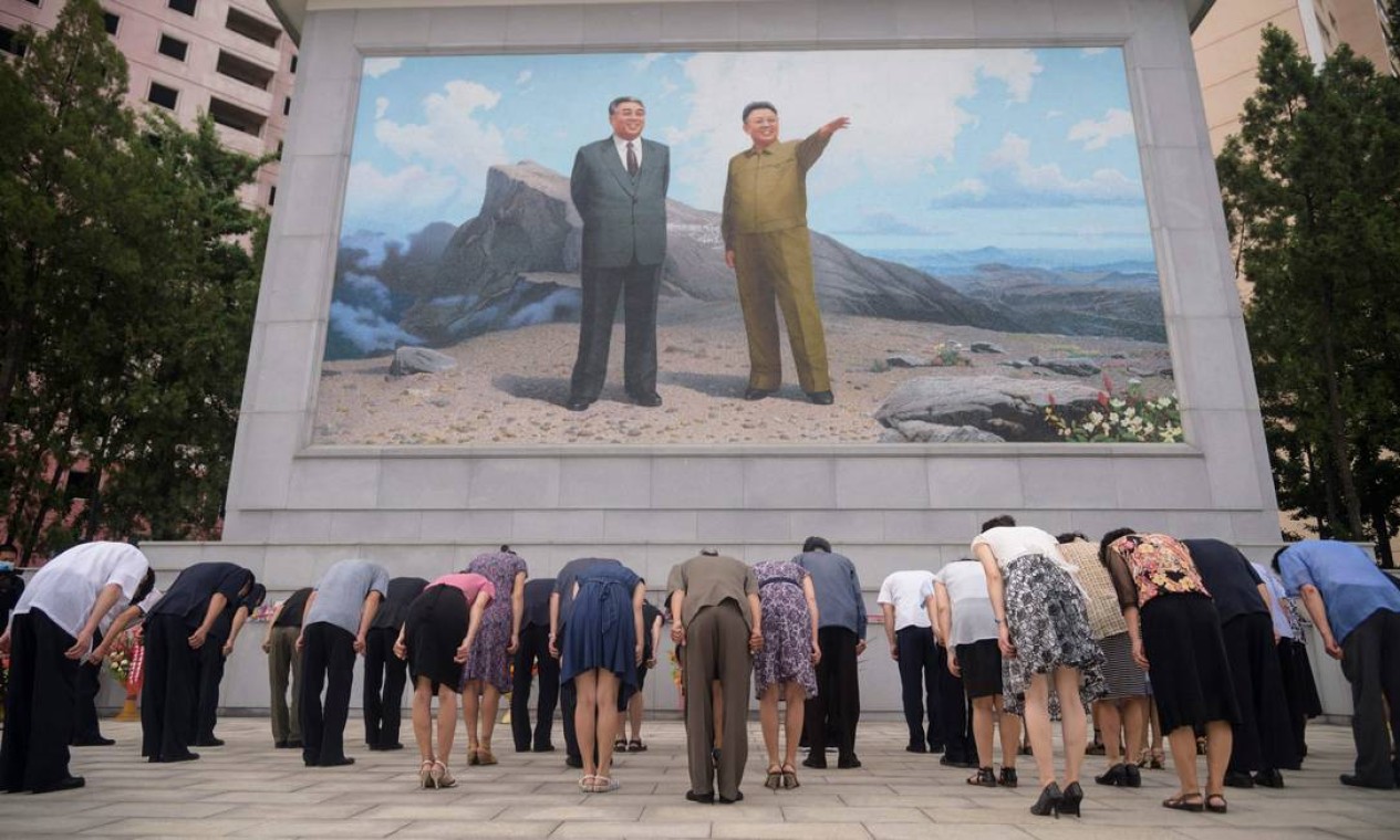 Pessoas se curvam diante de um mosaico de retratos dos falecidos líderes norte-coreanos Kim Il Sung e Kim Jong Il, na encruzilhada Dongmun, no distrito de Daedonggang de Pyongyang, por ocasião do 27º aniversário da morte de Kim Il Sung Foto: KIM WON JIN / AFP
