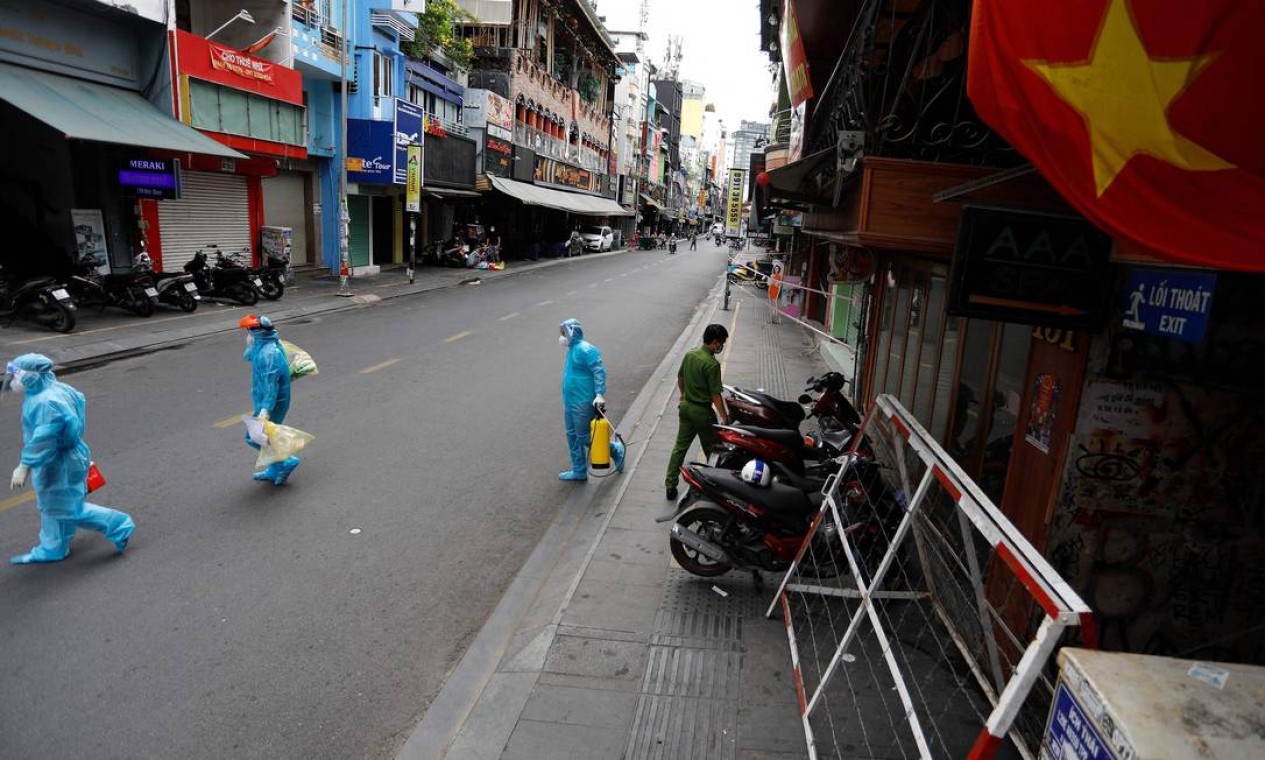 Trabalhadores médicos coletam amostras de teste de residentes passam pela cidade de Ho Chi Minh, no primeiro dia em que o governo impôs bloqueio de duas semanas como medida preventiva para impedir a disseminação do coronavírus COVID-19, no Vietnã Foto: HUU KHOA / AFP