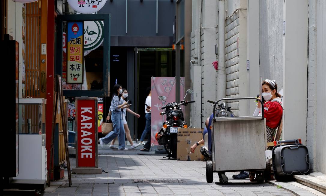Funcionária descansa do lado de fora da loja em Seul, Coreia do Sul Foto: HEO RAN / REUTERS