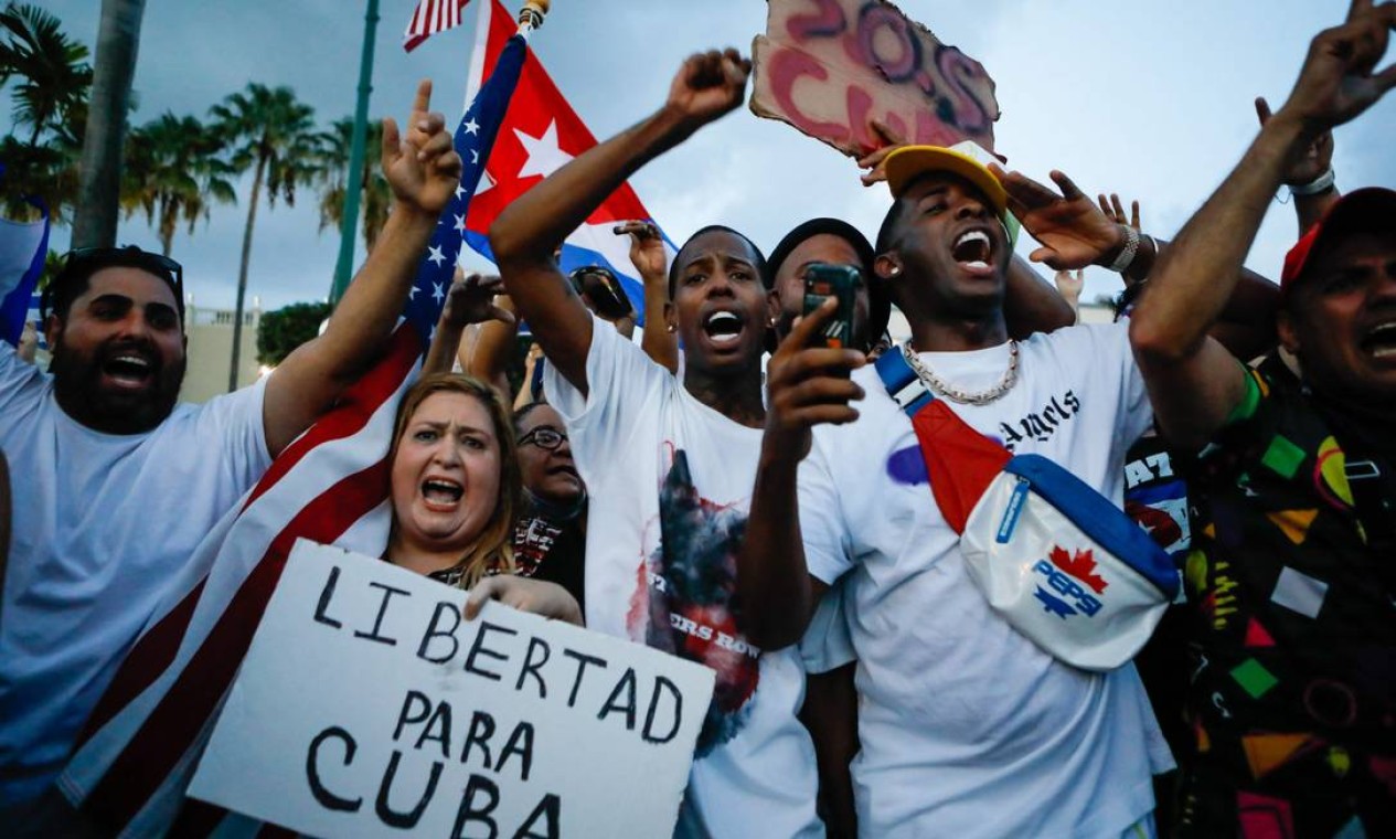 Mulher exibe cartaz com os dizeres "Liberdade para Cuba", enquanto outras pessoas protestam com bandeiras nacionais de Cuba e dos Estados Unidos durante um ato contra o governo cubano, em Miami, nos EUA Foto: EVA MARIE UZCATEGUI / AFP