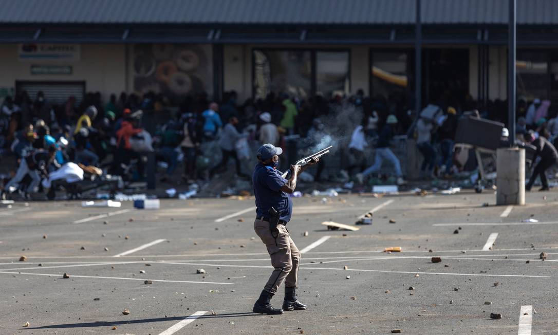 Policial da África do Sul dispara balas de borracha na direção de pessoas saqueando o Shopping Jabulani, na cidade de Soweto Foto: Guillem Sartorio / AFP